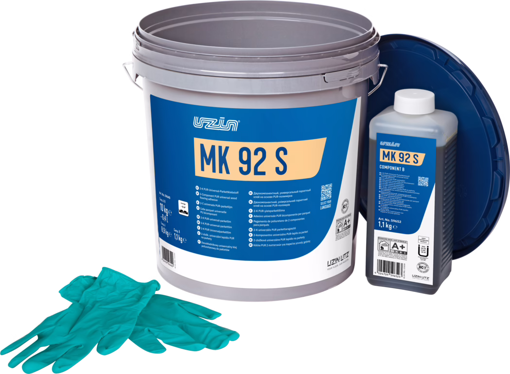 UZIN_Dummy_MK 92 S-10kg_2024-09 Studiijska fotografija komplet za lepilo za parket: velika siva plastična vedra z modrim etiketom 'MK 92 S', desno manjša pravokotna steklenica z oznako 'MK 92 S Component B' in belo zamaškom, v ozadju se naslanja temno moder pokrov. V ospredju je par turkiznih enkratnih rokavic. Predmeti so postavljeni na belo ozadje in enakomerno osvetljeni, poudarjajo podrobnosti embalaže in informacije o izdelku za polaganje tal.